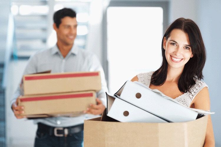 Two employees caring moving boxes to their new office